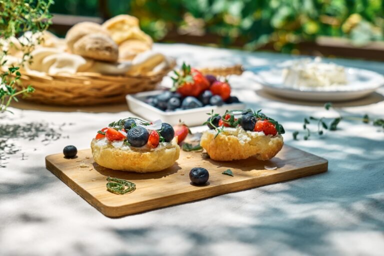 Toast with cream cheese, blueberry, strawberry, coconut flakes and herbs for summer picnic or brunch. Sweet mini sandwiches for healthy breakfast in the garden.