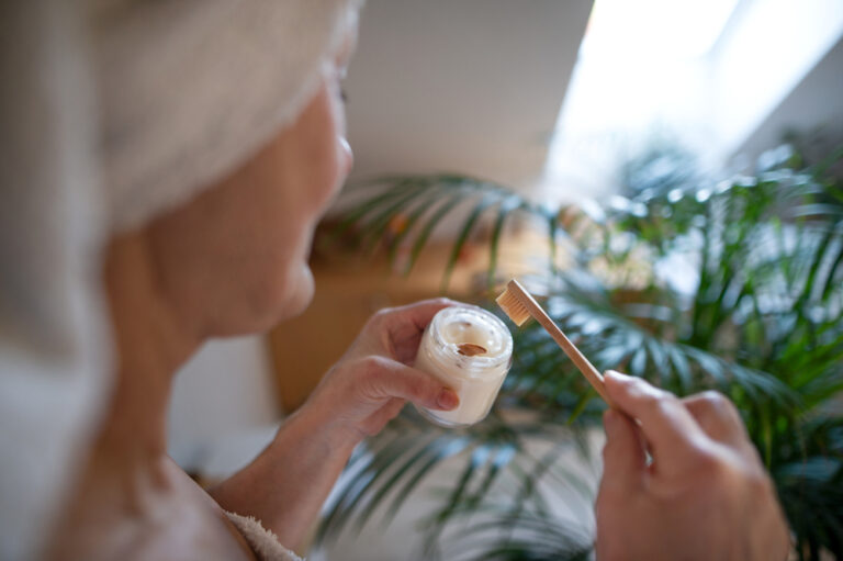 Unrecognizable senior woman in bathroom brushing teeth at home, ecologic and sustainabke lifestyle.