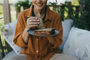 Beautiful woman relaxing in the garden, eating sandwich. Mother having moment to herself while her child is sleeping, eating lunch or dinner in peace.