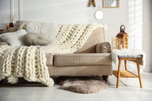 Cozy living room interior with beige sofa, knitted blanket and cushions